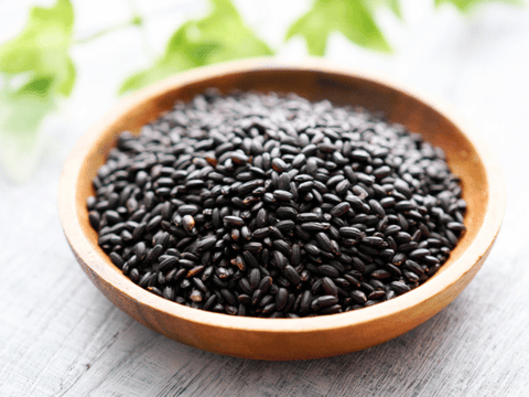 Bowl of black rice and white tea cup on rustic table – Indian superfoods